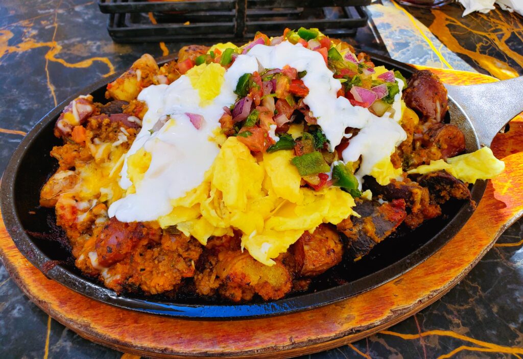 The Texas Skillet with marinted ground beef, potatoes, Pico de Gallo, mixed melted cheese, sour cream, and two eggs any style